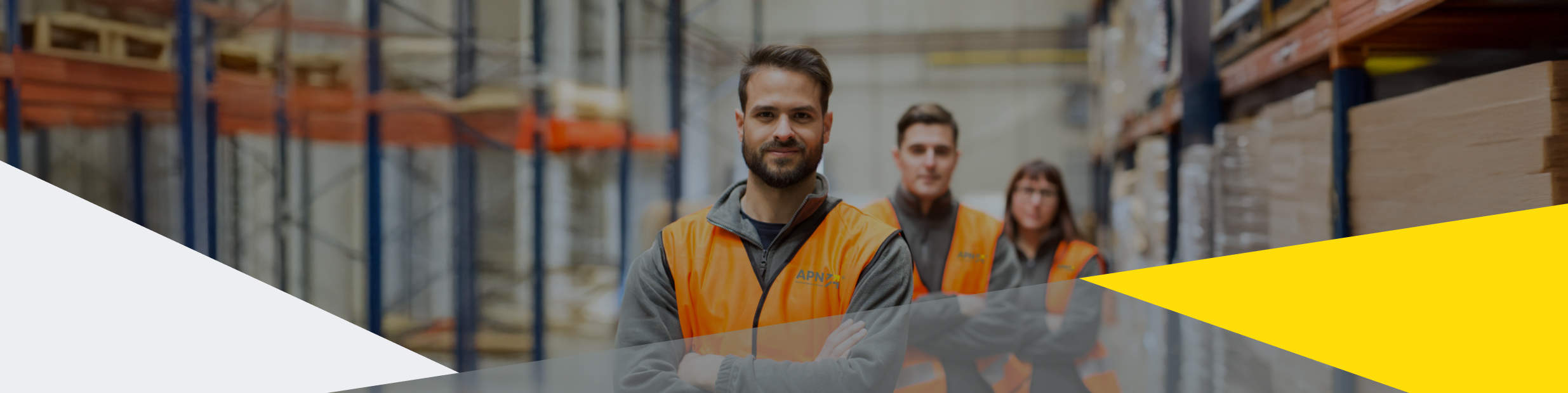 Drei APN Mitarbeiter in Westen stehen im Lager für die Personaldienstleistung Logistik bereit.