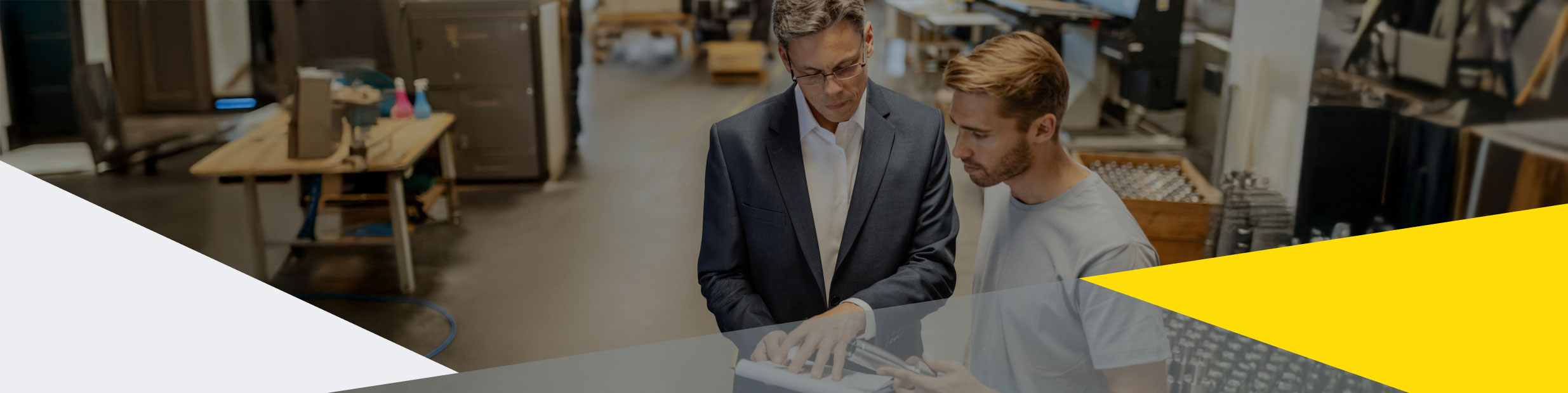 Ein Berater bespricht Dokumente mit einem Kandidaten für eine transparente Personalvermittlung in der Produktion.